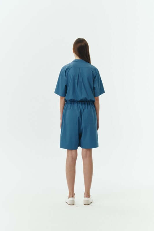 Back view of a woman wearing the Emma Solid Jumpsuit, showcasing its relaxed structure and breathable fabric.