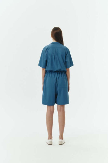 Back view of a woman wearing the Emma Solid Jumpsuit, showcasing its relaxed structure and breathable fabric.