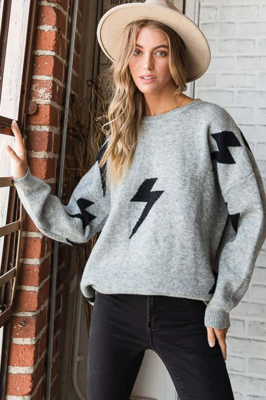 BOLT LONG SLEEVE CREW NECK SWEATER featuring lightning print model wearing it with stylish hat by window