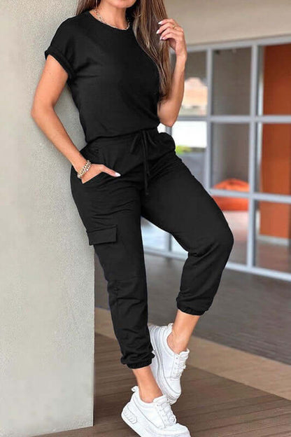 Crew Neck Short Sleeve Drawstring Waist Jumpsuit in black, styled with white sneakers, ideal for casual outings.