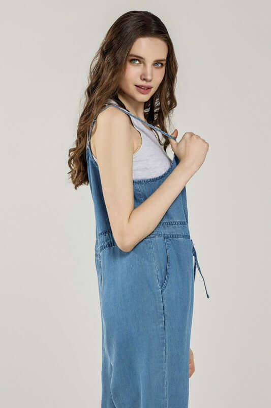 Model wearing a Plus Pocket Adjustable Straps Overall Jumpsuit in denim, showcasing its stylish side profile.
