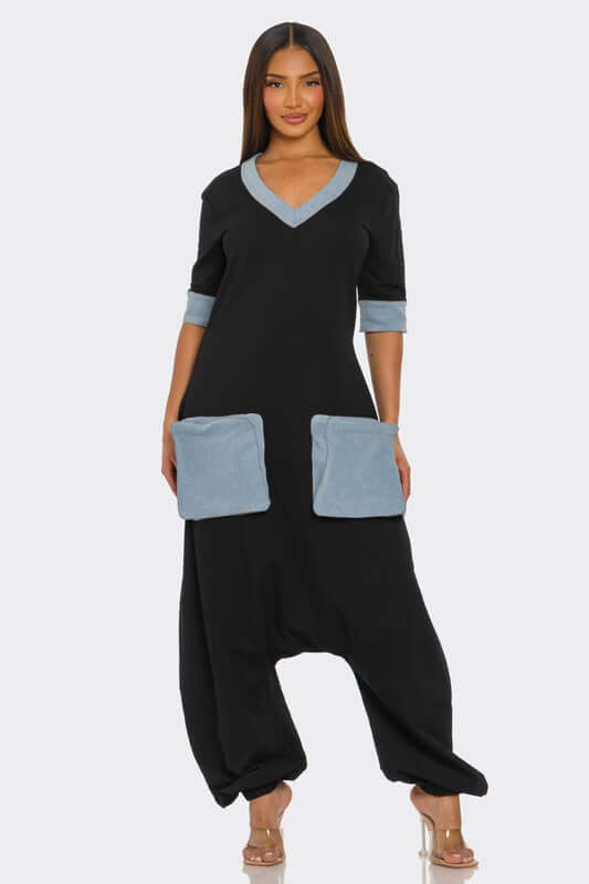 Model wearing the Denim Accent Jumpsuit featuring a V-neckline, elbow-length sleeves, and oversized patch pockets.
