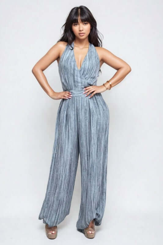 Model wearing a Skyline Halter Jumpsuit in blue with deep V-neckline and wide-leg trousers.