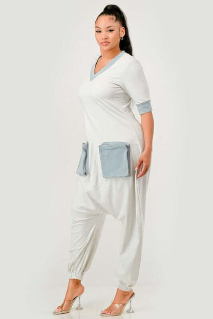 Model showcasing the Denim Accent Jumpsuit featuring V-neck, denim-trimmed sleeves, and oversized patch pockets.