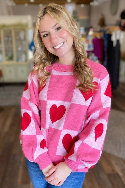 Woman wearing Love Heart Checkered Valentine Crew Neck Sweater in a cozy room.