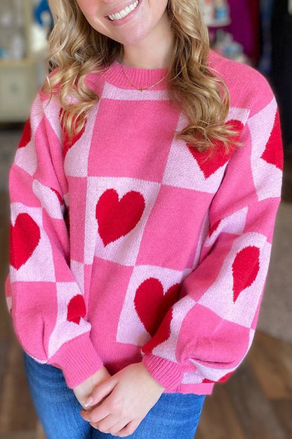 Woman wearing Love Heart Checkered Valentine Crew Neck Sweater in pink with heart pattern, perfect for Valentine's Day and daily wear.