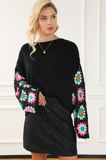Woman wearing Black Floral Crochet Bell Sleeve Loose Sweater with colorful floral designs, showcasing a relaxed fit and boat neckline.