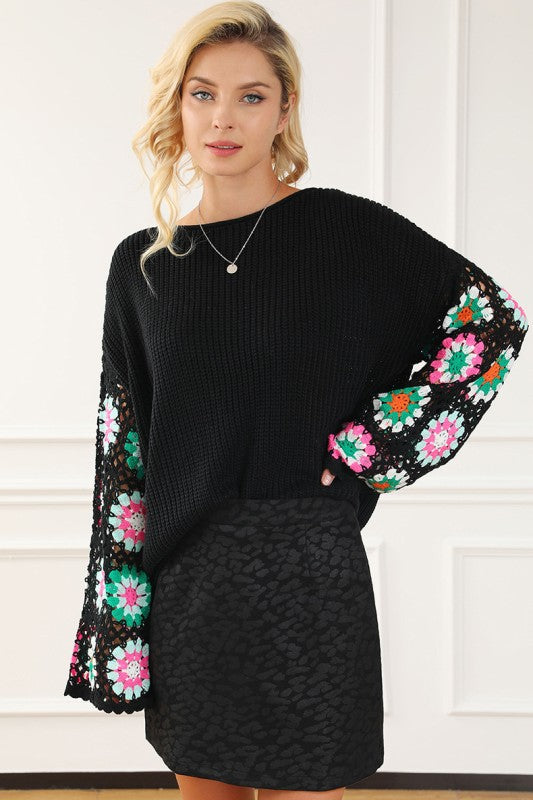 Black Floral Crochet Bell Sleeve Loose Sweater with delicate crochet sleeves and boat neckline, styled over a black skirt.