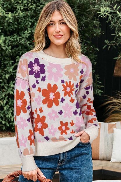 Woman wearing Floral Ribbed Trim Drop Shoulder Sweater with colorful floral design, relaxed fit, and ribbed cuffs, ideal for autumn layering.