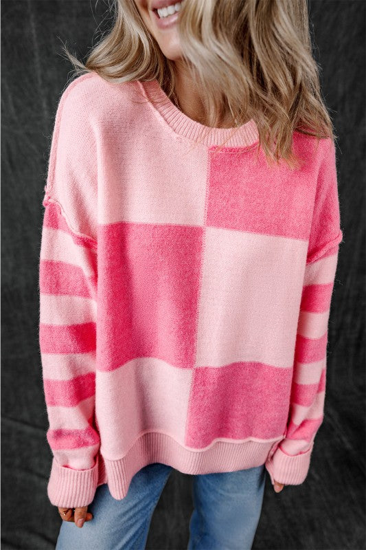 Woman wearing Abigail High Low Loose Sweater in pink with colorblocking and stripes, modern asymmetric hem, and relaxed fit.