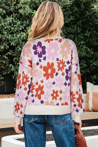 Back view of a woman wearing a Floral Ribbed Trim Drop Shoulder Sweater with vibrant floral print, paired with jeans.