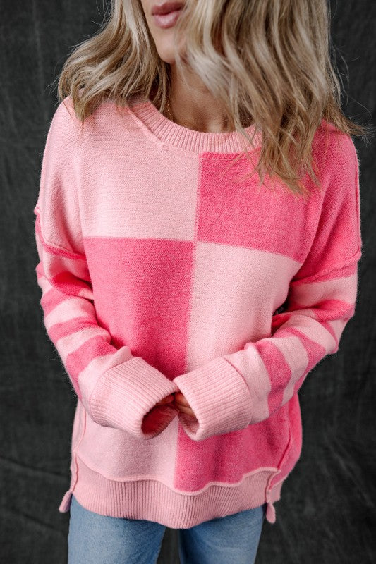 Woman wearing Abigail High Low Loose Sweater in pink with colorblocking and stripes, showcasing a modern high-low hem.