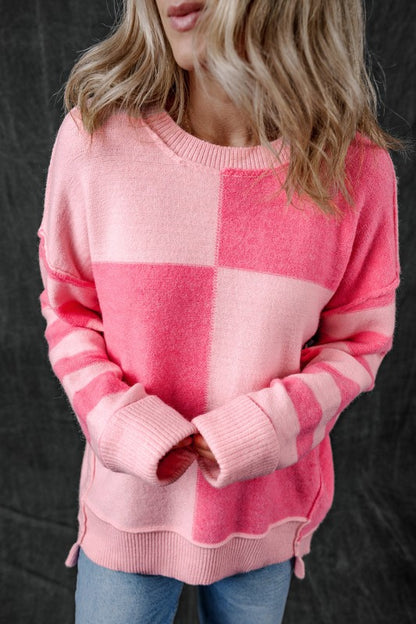 Woman wearing Abigail High Low Loose Sweater in pink with colorblocking and stripes, showcasing a modern high-low hem.