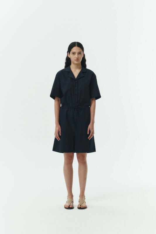 Model wearing the Emma Solid Jumpsuit in dark color, showcasing its camp collar and relaxed fit.