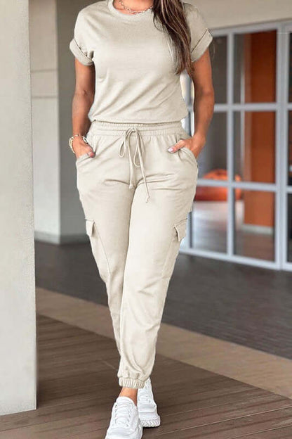Woman wearing a Crew Neck Short Sleeve Drawstring Waist Jumpsuit in beige, perfect for casual outings and daily wear.