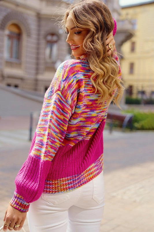 Woman wearing a Rainbow Confetti Patchwork Drop Shoulder Sweater on a city street, showcasing vibrant colors and casual style.
